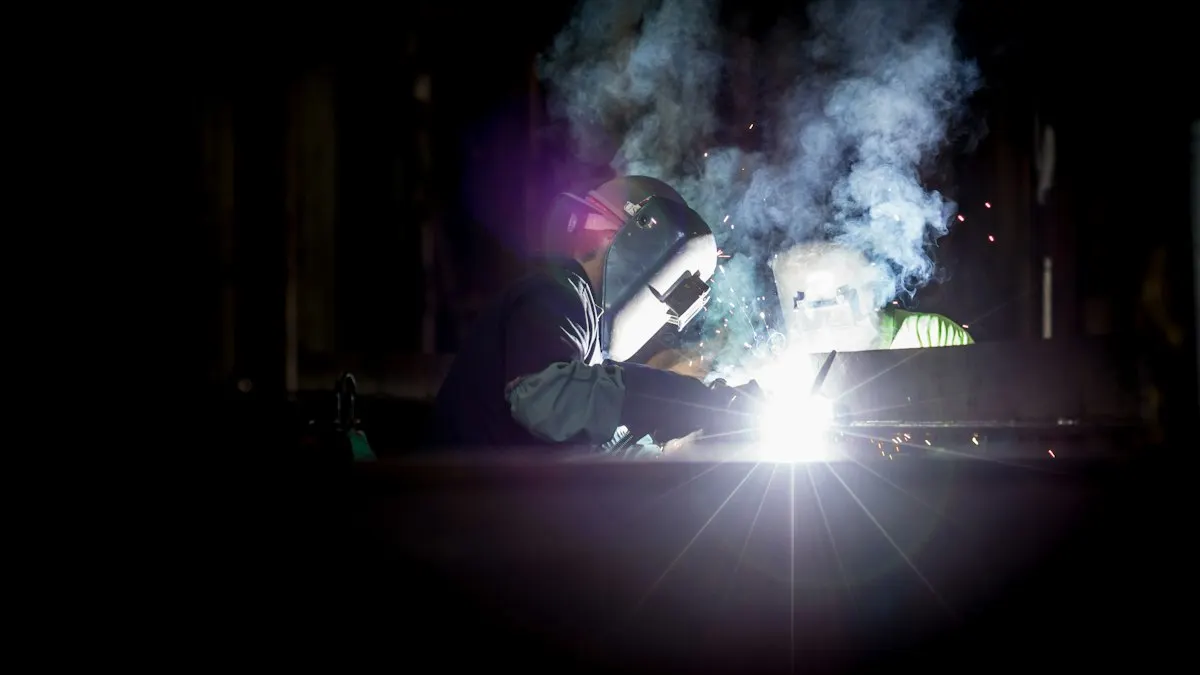 Welder in a gray helmet working in a fabrication shop