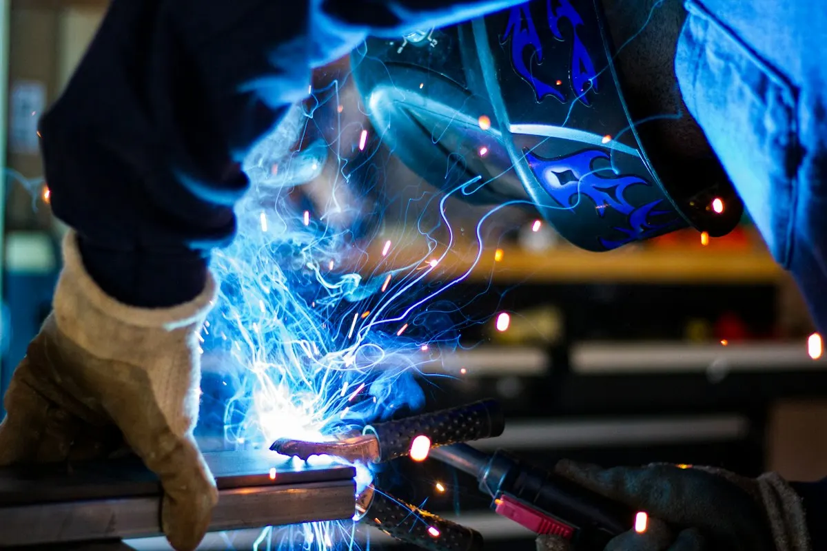 Welder in a protective helmet working on metal with sparks flying